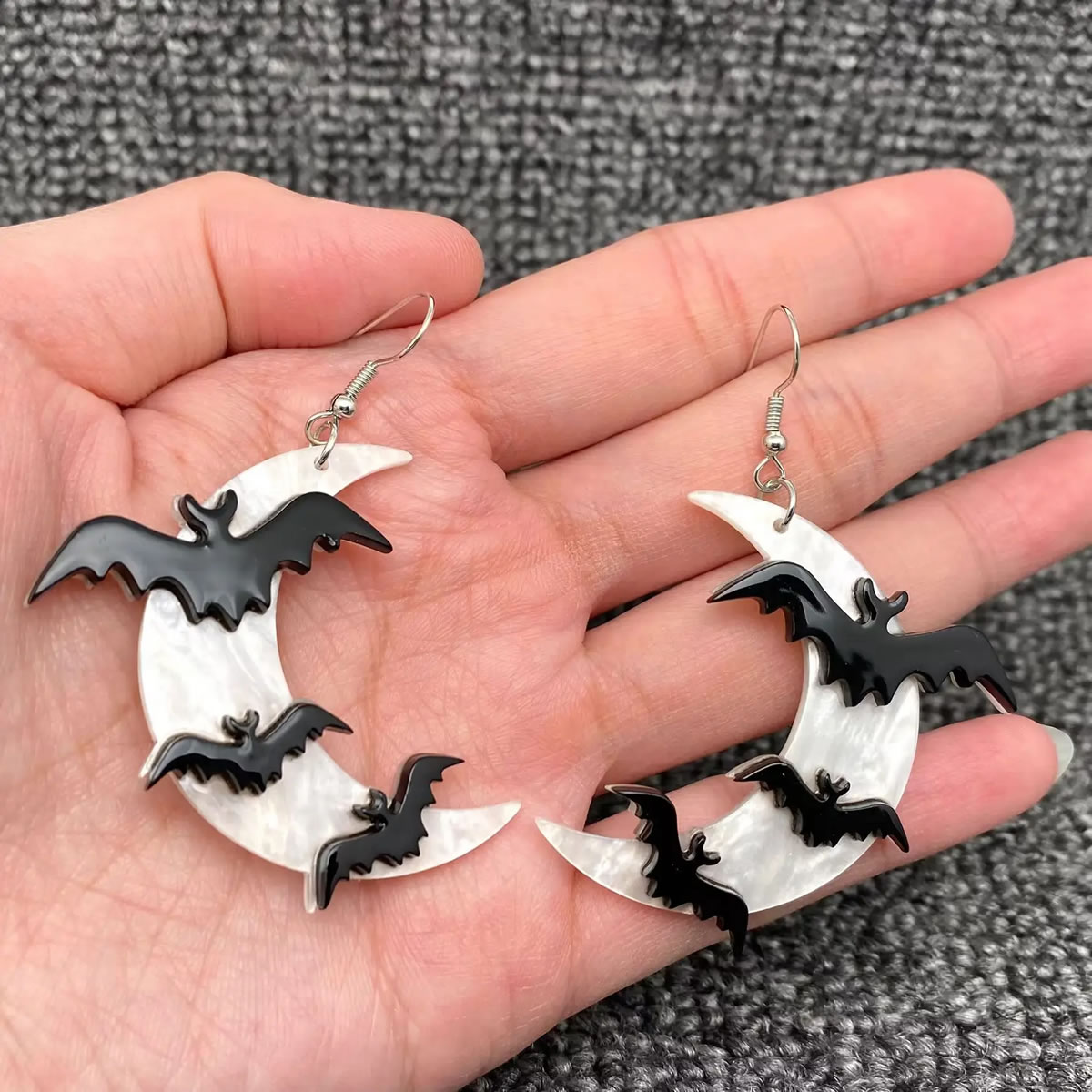 Night Flight Bat Moon Earrings featuring pale crescent moon shapes decorated with black flying bat silhouettes, suspended from silver-tone ear wires.