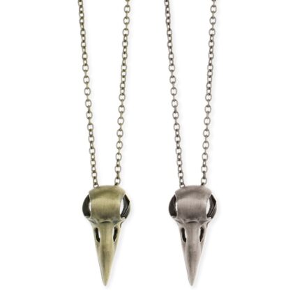 old-tone and silver-tone crow skull pendant necklaces displayed side by side on a white background.